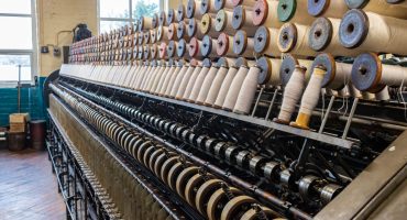 This image depicts a modern industrial machine used to create cone-shaped spools of yarn, providing material necessary for knitting projects