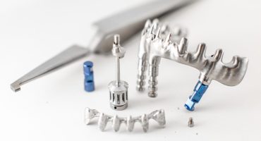 Close-up studio shot on milled metal frame for dental implants on the white background. Concept of new technologies in dental prosthetics